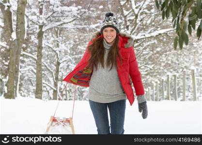 Young woman in snow with sledge