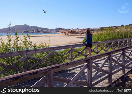Young woman in sports clothes walking by a wooden walkway in Playa America, Vigo