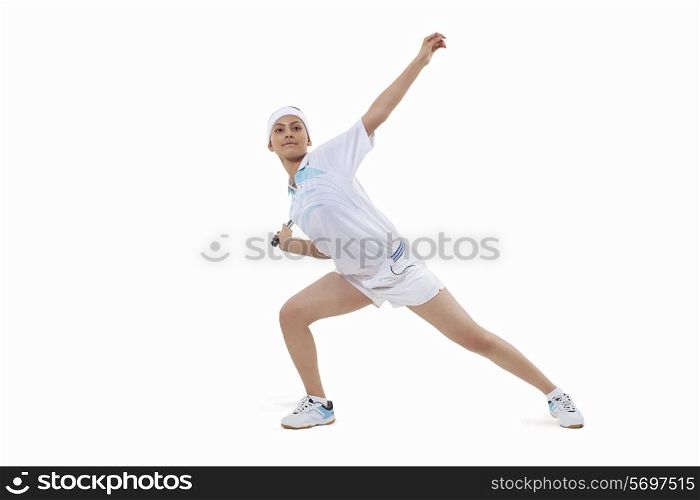 Young woman in sports wear playing badminton isolated over white background