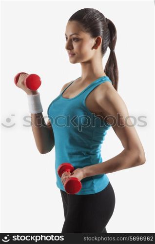 Young woman in sportswear exercising against white background