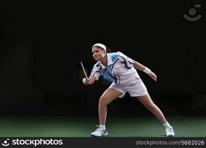 Young woman in sportswear playing badminton over black background