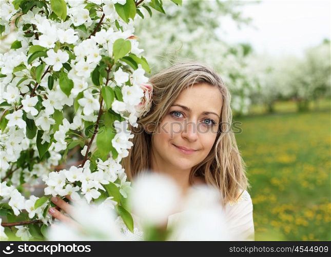 young woman in spring park among flowers