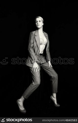 Young woman in suit and bra on black background. Full length portrait