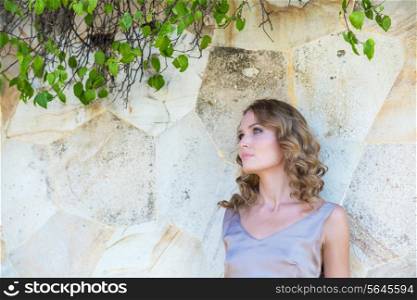 Young Woman in Summer Dress Against Old Stone Wall, Outdoor Shot