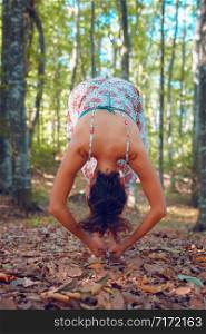Young woman in summer dress in the forest woods in autumn doing yoga stretching in peace balance spirituality and nature concept