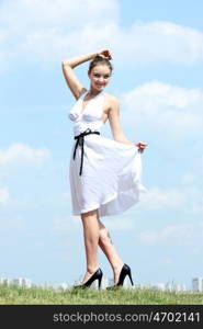 Young woman in summer dress on a background of the blue sky