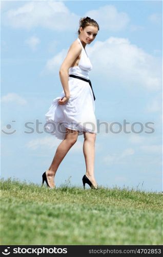 Young woman in summer dress on a background of the blue sky