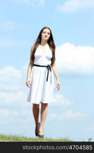 Young woman in summer dress on a background of the blue sky