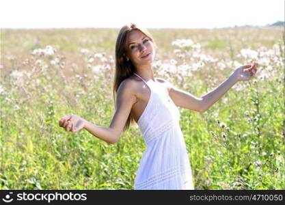 Young woman in summer dress walking on a meadow