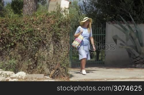 Young woman in summer hat walking in search of room to hire. She meeting a pointer with needed information and following it