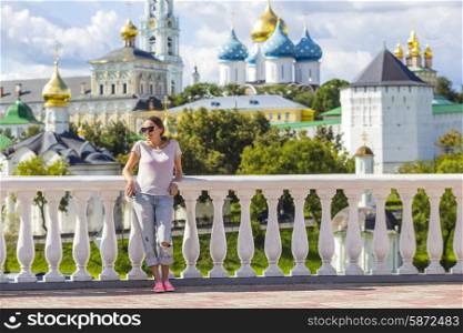 Young Woman in Sunglasses with Trinity Sergius Lavra in Sergiev Posad in background.Moscow region. Russia.released