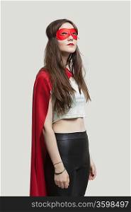 Young woman in superhero costume looking up against gray background