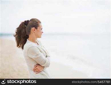 Young woman in sweater on beach looking into distance