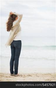 Young woman in sweater relaxing on lonely beach
