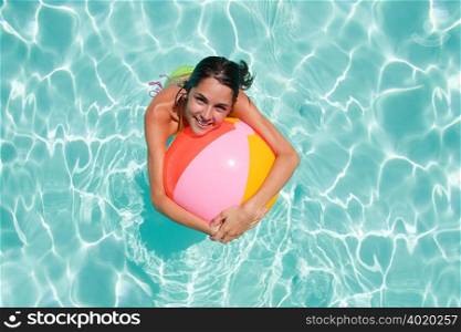 Young woman in swimming pool with beach ball