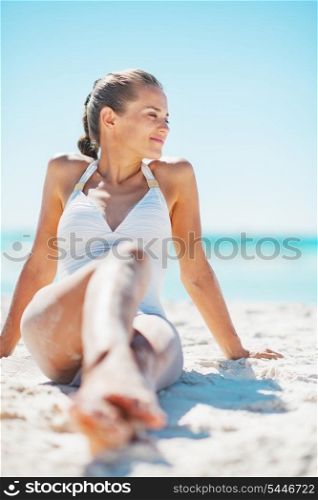 Young woman in swimsuit enjoying sitting on beach
