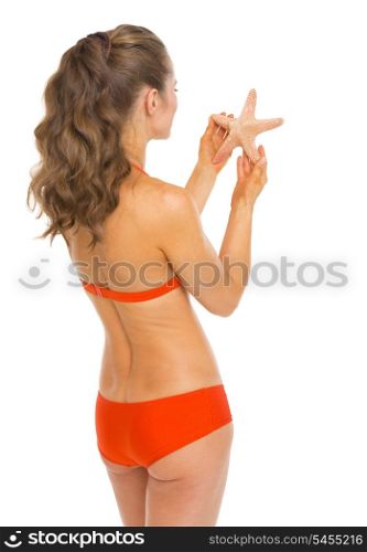 Young woman in swimsuit holding starfish . rear view