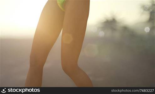 young woman in swimsuit near palms at sunset. Young Woman in Swimsuit at Sunset