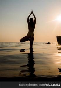 young woman in swimsuit practicing yoga at amazing sunrise. Fitness, sport, yoga and healthy lifestyle concept. Girl doing exersices in sea water.. young woman in swimsuit practicing yoga at amazing sunrise. Fitness, sport, yoga and healthy lifestyle concept. Girl doing exersices in sea water