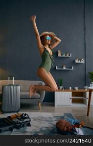 Young woman in swimsuit represent herself on beach jumping in home living room. Dreams about resort. Woman in swimsuit represent herself on beach
