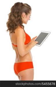 Young woman in swimsuit using tablet pc . rear view