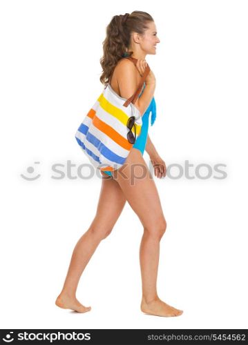 Young woman in swimsuit with beach bag going sideways