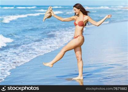 Young woman in swimwear and sunhat, enjoying the beach on her holiday.. Woman in swimwear and sunhat, enjoying the beach on her holiday.