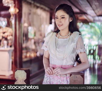 young woman in Thai traditional dress at wooden house