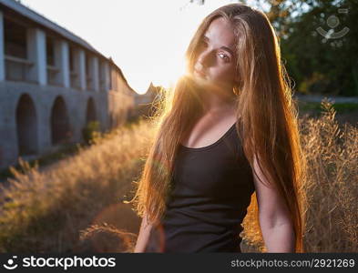 Young Woman In The Autumn Park at Sunset. Backlit. Picture of beautiful female over sunset, closeup portrait of romantic girl, attractive blond woman enjoying autumn golden sunlight, pretty young lady outdoors rejoice of warm weather at fall season