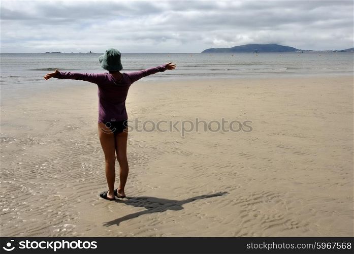young woman in the beach with arms wide open