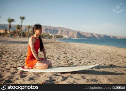 Young woman in the beach with her surf table waiting in the sand