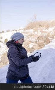 Young woman in the snow mountains landscape on holiday holding natural soft white snow in her hands to make a snowball