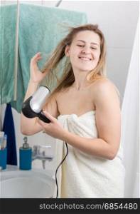 Young woman in towel drying hair at bathroom