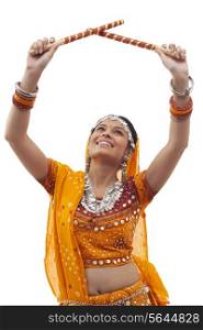 Young woman in traditional wear performing Dandiya Raas over white background