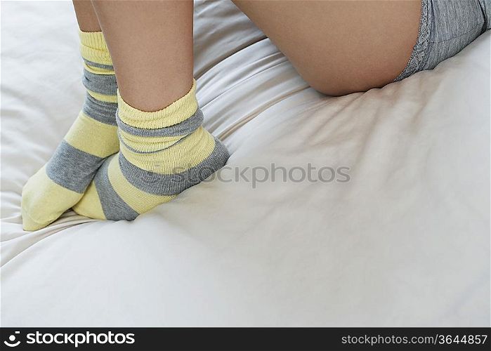 Young woman in underwear on bed, low section