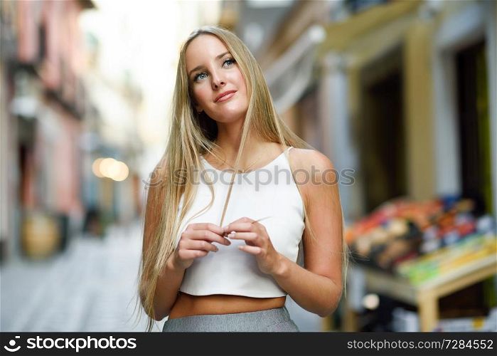 Young woman in urban background. Blond girl wearing with nice hair casual clothes in the street. Straight hairstyle.