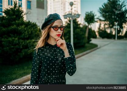 young woman in vintage black polka dot dress posing outside