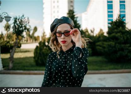young woman in vintage black polka dot dress posing outside