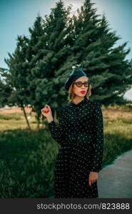 young woman in vintage black polka dot dress posing outside