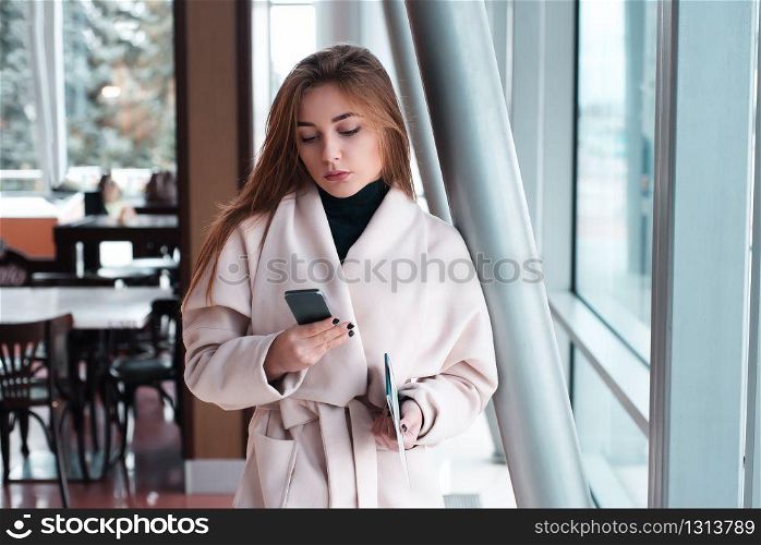 Young woman in waiting room of international airport, checking her phone.
