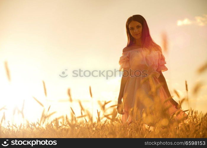 Young woman in wheat field at sunset