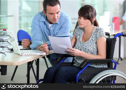 Young woman in wheelchair working with a male colleague
