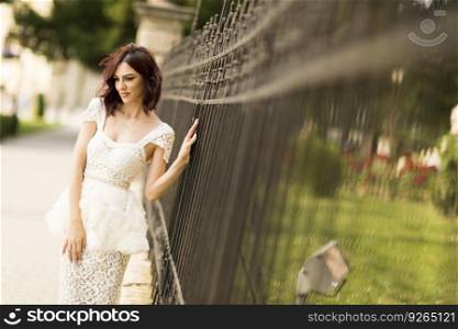 Young woman in white drress by the fence