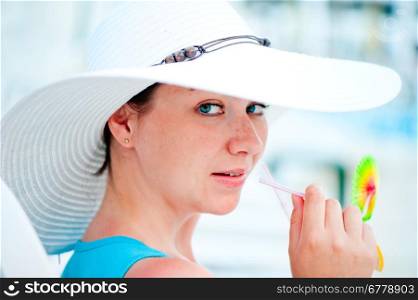 young woman in white hat drinking a cocktail