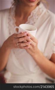 Young woman in white silk robe with white cup of beverage tea or coffee in the morning.. Young woman in white silk robe with white cup of beverage tea or coffee in the morning