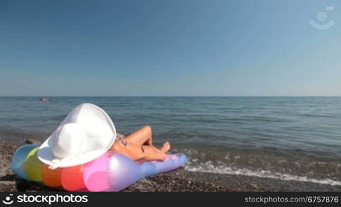 young woman in white sun hat tanning on beach