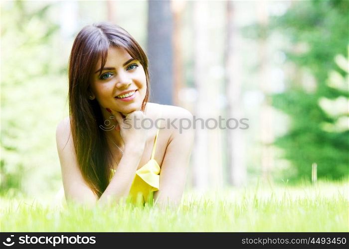 young woman in yellow dress lying on grass. beautiful young woman in yellow dress lying on grass
