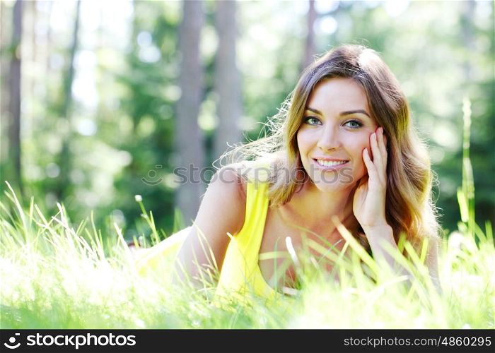 young woman in yellow dress lying on grass. beautiful young woman in yellow dress lying on grass