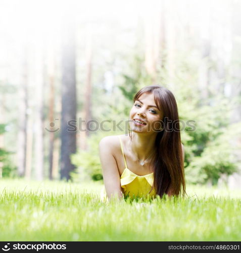 young woman in yellow dress lying on grass. beautiful young woman in yellow dress lying on grass