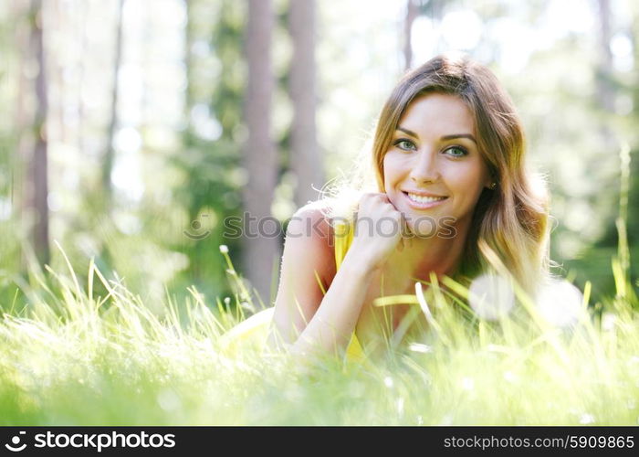 young woman in yellow dress lying on grass. beautiful young woman in yellow dress lying on grass